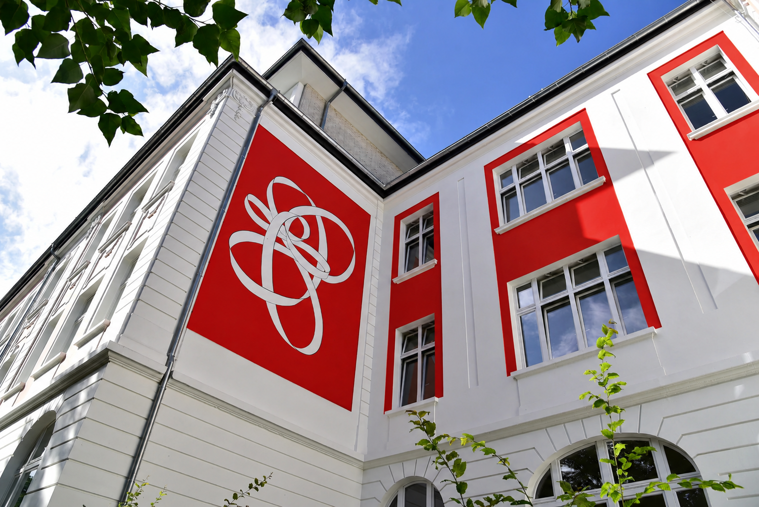 Wichels Maler Home Frisch gestaltete Gebäudefassade mit dekorativen Fassadenelementen, großen Fenstern und hochwertiger Beschichtung an einem historischen Gebäude.